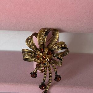 Vintage gold-toned floral and bow brooch featuring amber-colored rhinestones